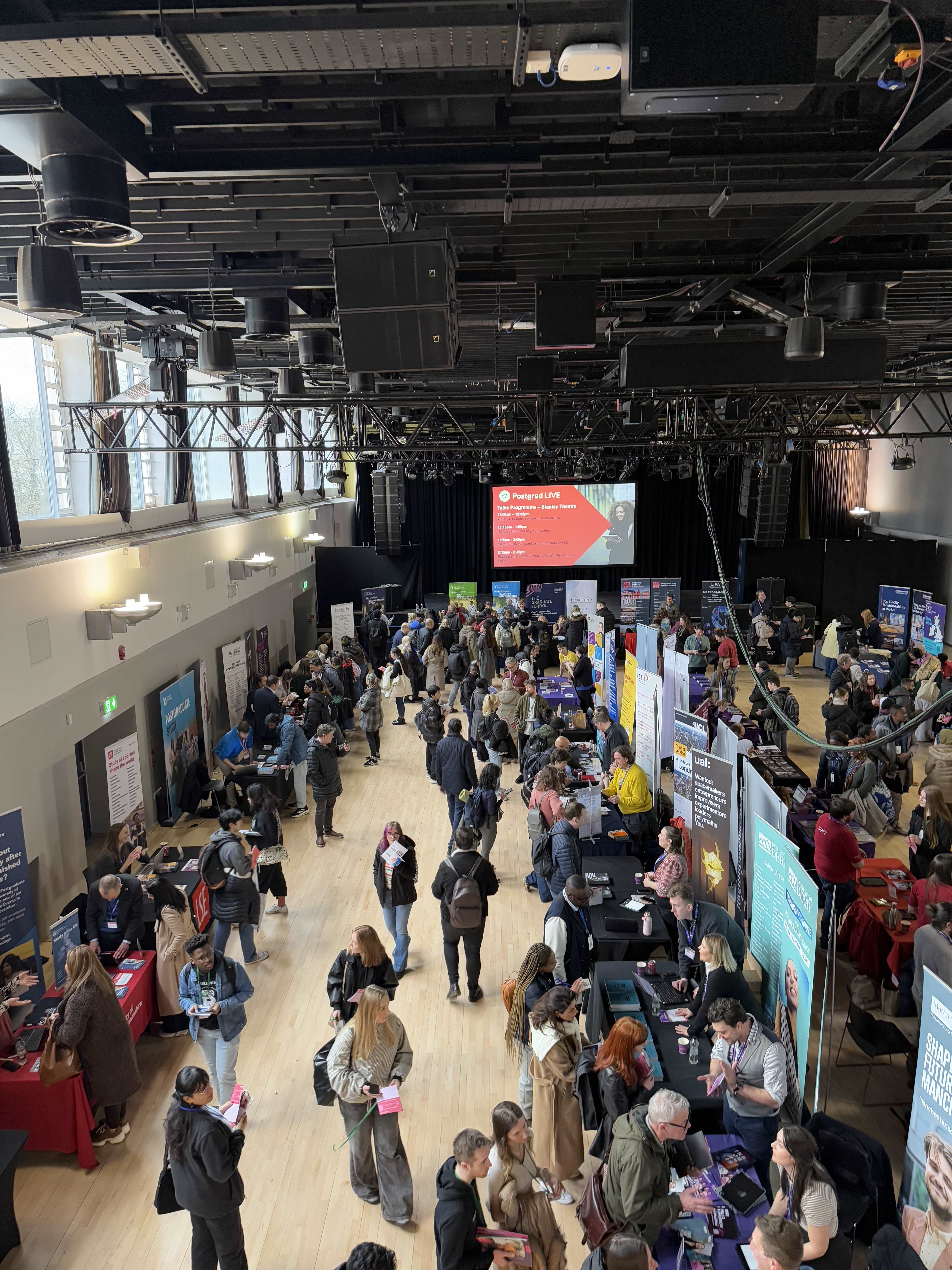 Students speaking with university exhibitors at Postgrad LIVE