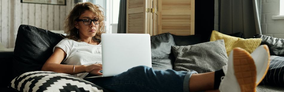 Woman sat on sofa with laptop on lap and feet up
