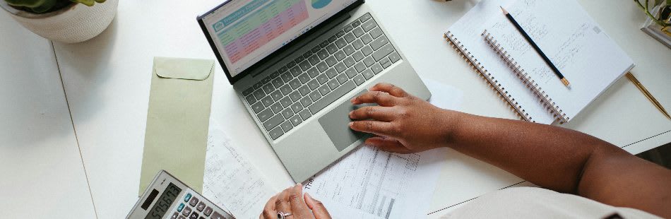 A person sitting at a table with a laptop and calculator