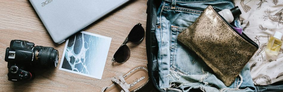 Packing for travel with a camera, laptop, clothes and suitcase