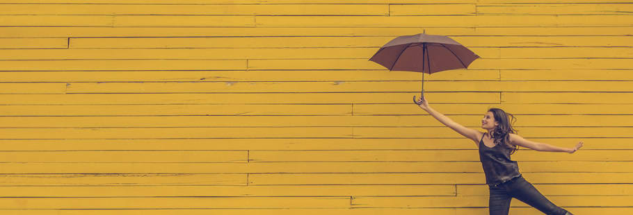 Woman with umbrella on yellow wood background
