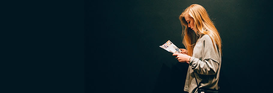 Woman reading from a brochure, set against a black background