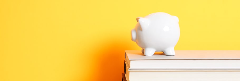 White piggy bank on books against yellow background