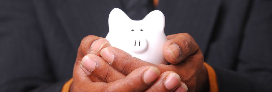 A small white piggy bank being held in hands