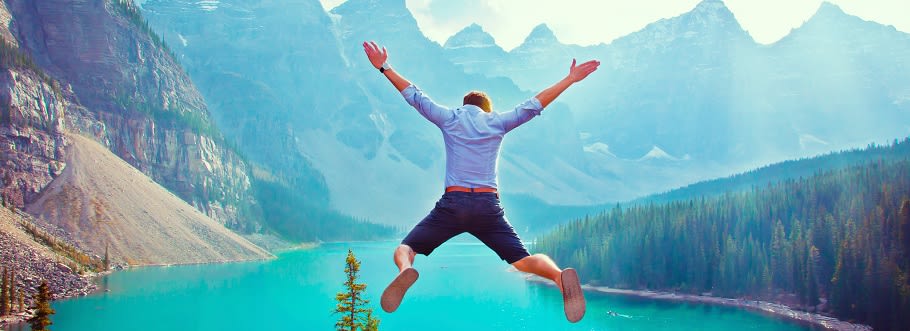 Man jumping into a star shape in front of lake and mountain