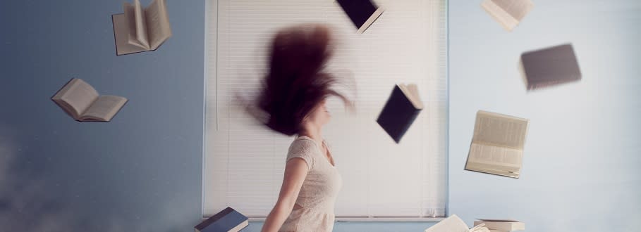 Girl throwing books in the air and flipping her hair back