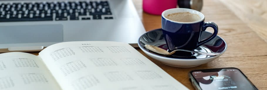 Laptop, phone, coffee and book on table