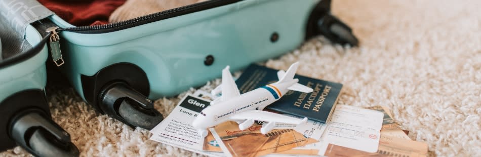 Open suitcase with model plane and passport on carpet