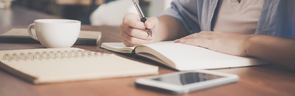 Desk with pen, paper and phone writing Masters application