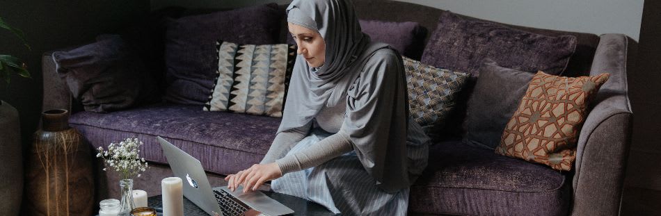 Woman in headdress sat in living room on laptop
